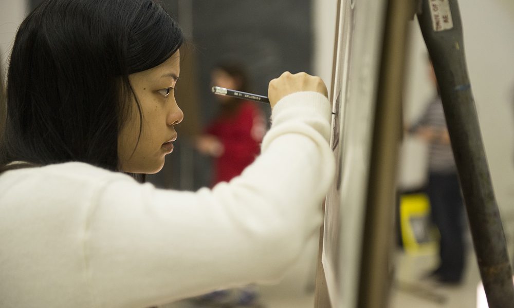 Female Student draws on canvas in Drawing I